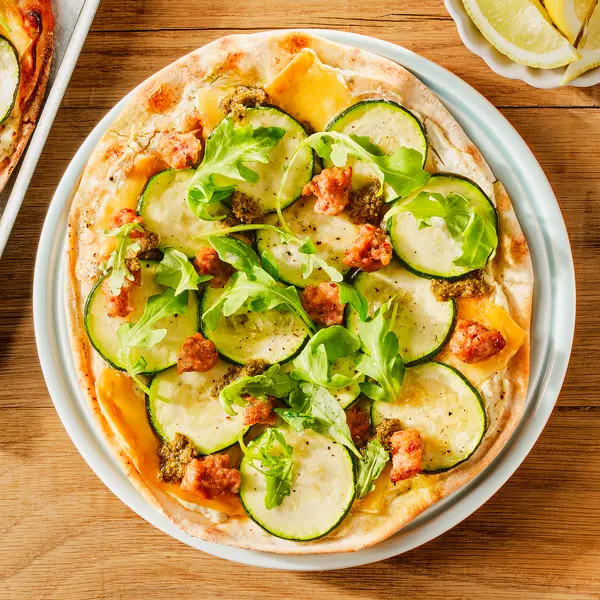 Platbroodpizza met oude kaas, worst en courgette