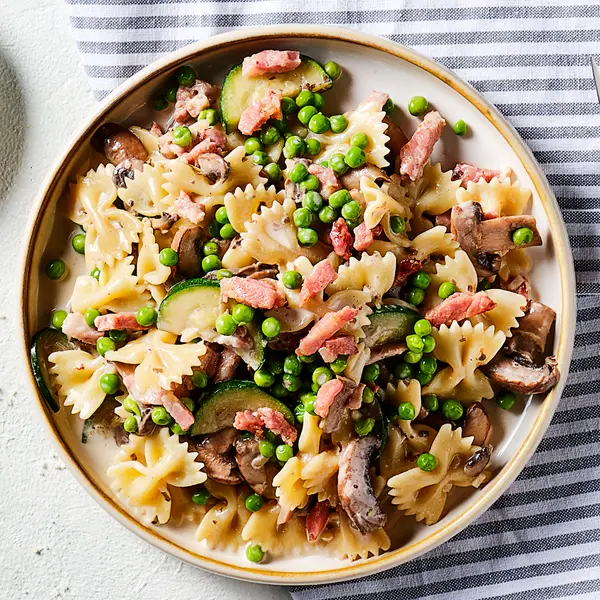 Romige farfalle met paddenstoelen en erwtjes