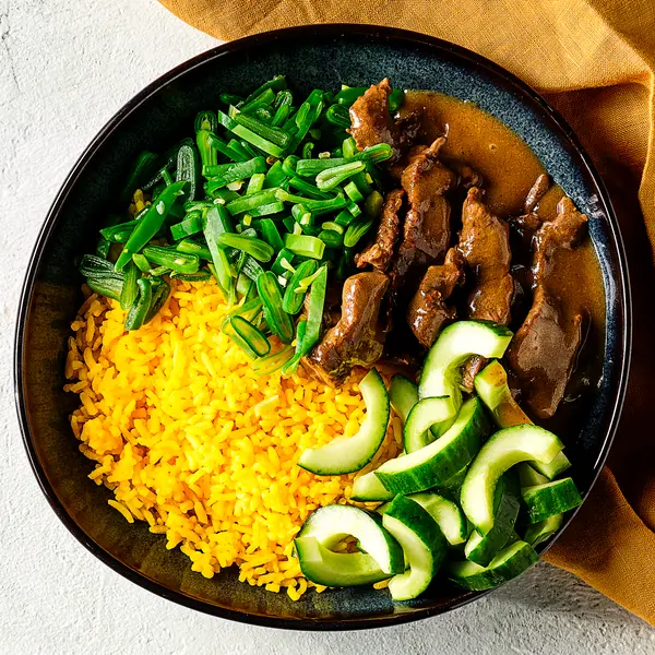 Snelle rendang met gele rijst en komkommer
